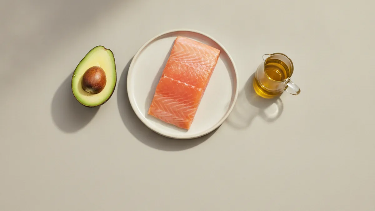 Salmón, medio aguacate y una jarrita de aceite de oliva vistos desde arriba